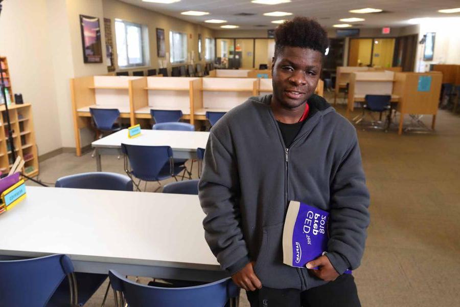 Student leaning on table with GED Studyguide